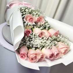 Pink roses with baby's breath in white wrapping and a pink ribbon