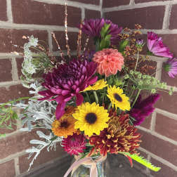 Mixed bouquet of bright chrysanthemums and sunflowers in a glass jar vase
