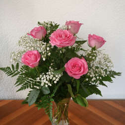 Pink roses arranged in a clear glass vase with white baby's breath