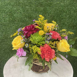 Mixed bouquet in a wicker basket with yellow roses and colorful blooms
