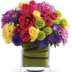 Mixed bouquet of roses, chrysanthemums, and other flowers in a glass vase