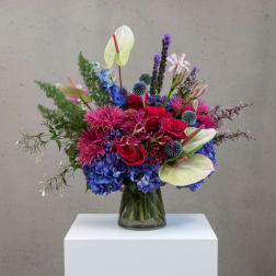 Colorful mixed bouquet in a glass vase with roses, hydrangeas, and anthuriums
