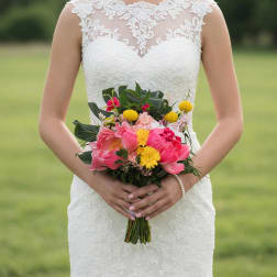 Bride holding a colorful bouquet of pink and yellow flowers