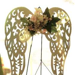 Floral arrangement on decorative angel wings with pale flowers and dark green leaves