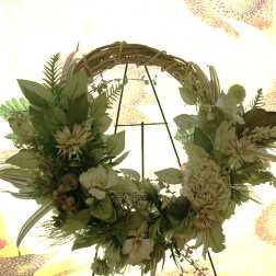 Floral wreath with cream flowers and green foliage on a metal stand