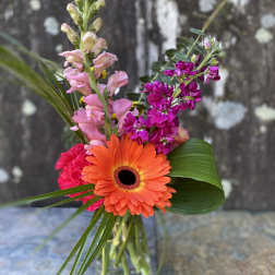 Mixed bouquet with an orange gerbera daisy and pink snapdragons in a glass vase