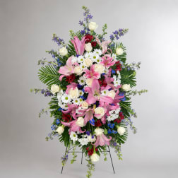 Standing floral spray with pink lilies, white roses, and daisies on an easel