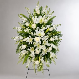 White lilies and roses in a standing floral spray with greenery