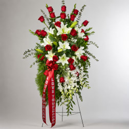 Standing floral spray of red roses and white lilies with a red ribbon