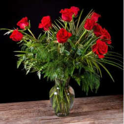 Red roses arranged in a clear glass vase with greenery