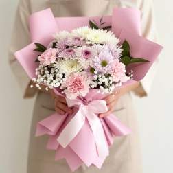 Pink-wrapped bouquet of pastel chrysanthemums with a white ribbon