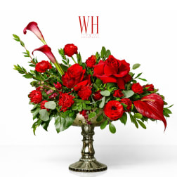 Red roses and calla lilies arranged in a silver pedestal vase