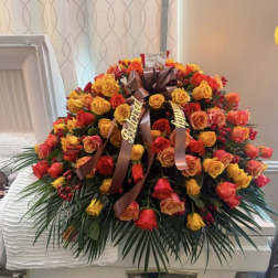 Large rose arrangement on a white casket with ribbon accents