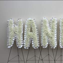 White floral letters spelling "NANDA" on black stands