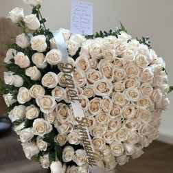 Heart-shaped bouquet of cream roses with a white ribbon and sympathy card