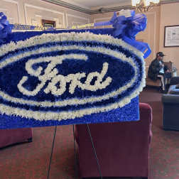 Blue and white floral Ford logo display on an easel with ribbon bows
