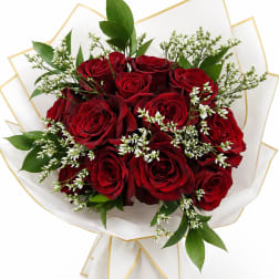 Bouquet of red roses with white filler flowers and green leaves in white wrap