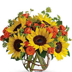 Sunflowers and orange roses arranged in a clear glass vase