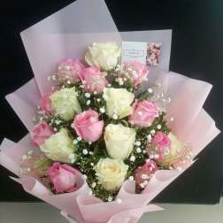 Bouquet of pink and white roses wrapped in pale pink paper