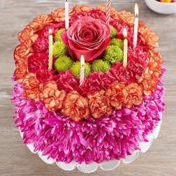 Round floral cake with a rose center and lit candles