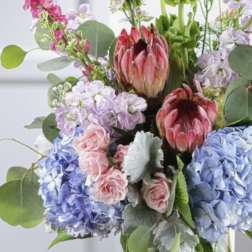 Mixed bouquet with protea, hydrangeas, roses, and tall green blooms