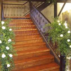 White floral arrangements line both sides of a wooden staircase.