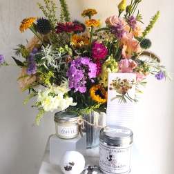Mixed bouquet in a metal vase with a note card and tea tins in front