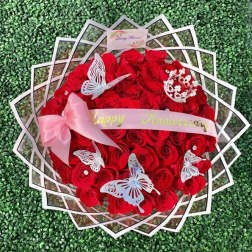 Round bouquet of red roses with pink ribbon and butterfly decorations