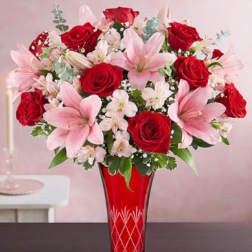 Tall bouquet of red roses and pink lilies in a red etched glass vase