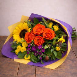 Bouquet of orange roses and a sunflower wrapped in purple and yellow paper