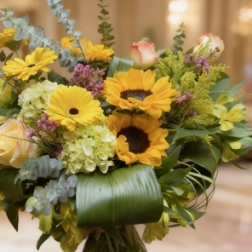 Bouquet of yellow sunflowers and pale roses in a glass vase