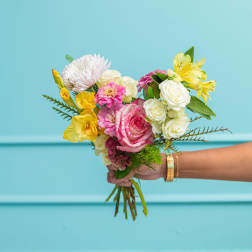 Handheld bouquet of pink, white, and yellow flowers