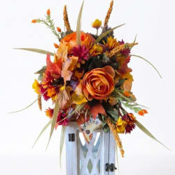 Autumn floral arrangement with orange blooms in a white lantern