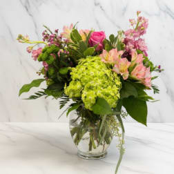 Mixed bouquet of pink and green flowers in a clear glass vase