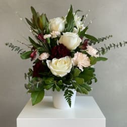 White roses and pale pink carnations in a white vase