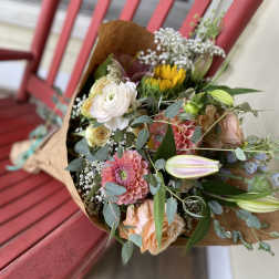 Mixed bouquet with pink, white, and peach flowers wrapped in brown paper