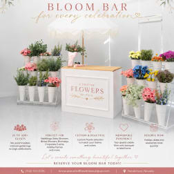 Bloom bar display with assorted flowers in white buckets under a canopy