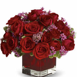 Red roses and pink filler flowers in a square glass vase