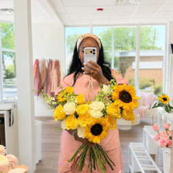 Woman holding a bouquet of yellow sunflowers and cream roses