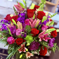 Bouquet of red roses, pink lilies, and purple flowers in a vase