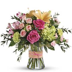Bouquet of pink roses, lilies, and green hydrangeas in a glass vase