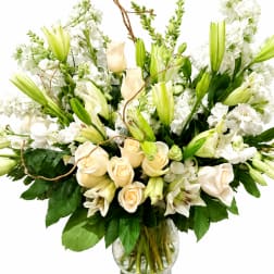 White lilies and cream roses arranged in a glass vase