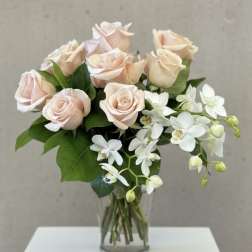 Blush roses and white orchids in a clear glass vase
