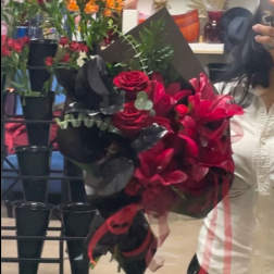 Bouquet of red roses and pink lilies wrapped in black paper