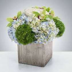 Blue hydrangeas and green pom-pom flowers in a square wooden container