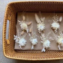 Basket of small dried floral boutonnieres in cream and beige tones