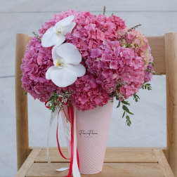 Pink hydrangea arrangement with white orchids in a pink vase