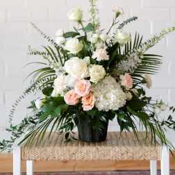 White and blush floral arrangement in a black vase