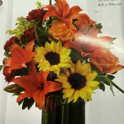 Orange lilies and sunflowers in a glass vase