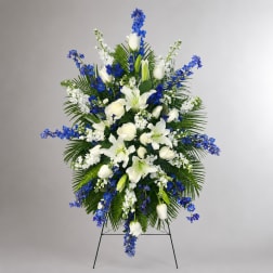 Standing floral spray with white lilies, roses, and blue flowers